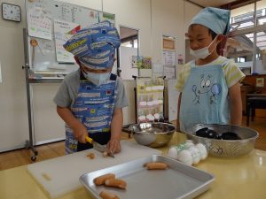 包丁の持ち方に気を付けてウインナーを切る子