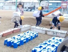 幼稚園のプランターに積もった雪をそっととる子どもたち