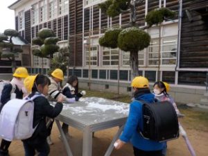 朝礼台の上の雪を集めています！