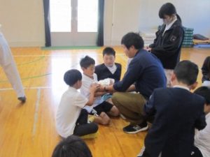 先生にささえてもらって赤ちゃん人形を抱っこする５年生