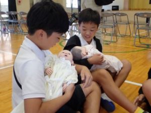２名が赤ちゃん人形を抱っこしてみつめている様子